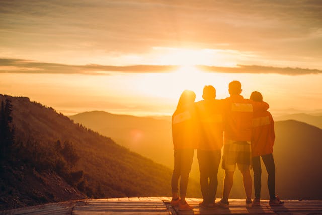 People Standing on the top of a Mountain during Sunset